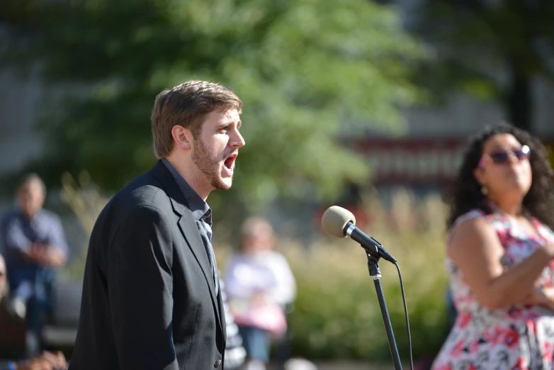 a man speaking into a microphone next to a woman holding a microphone