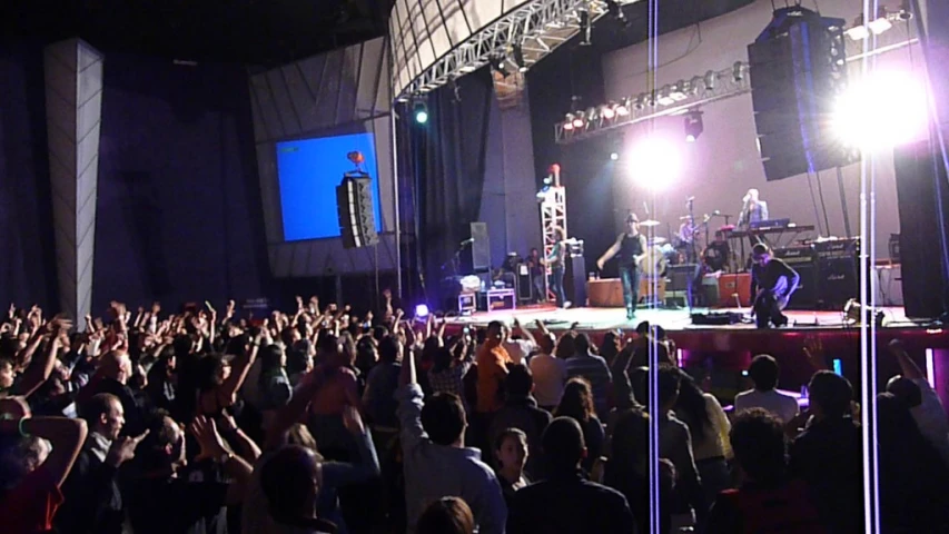 a crowd of people standing at a concert on stage
