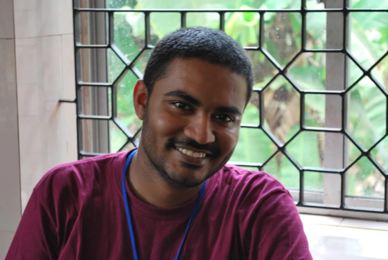 the man is smiling in front of a stained glass window