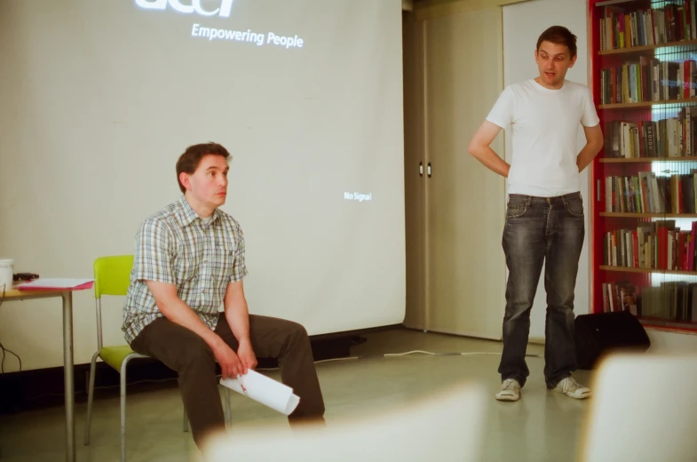 two men sitting on the ground in a liry with a projector