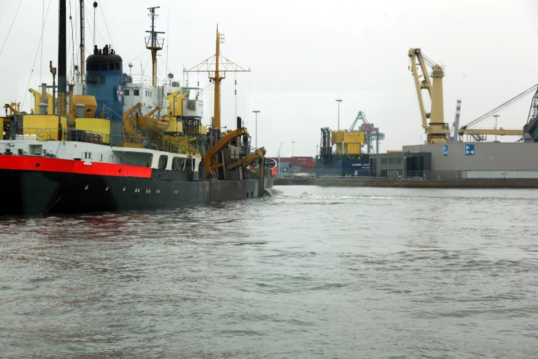 boats docked on water with cranes in background