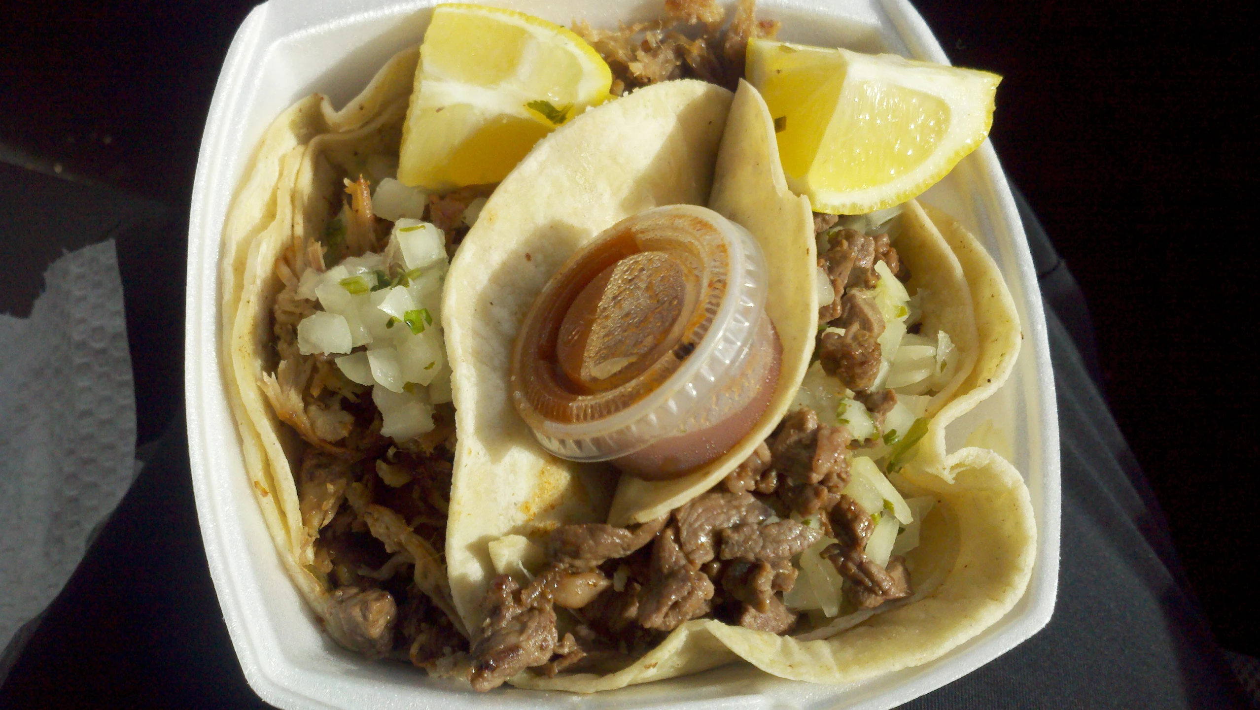 a taco with meat, onions and garnish on a tray