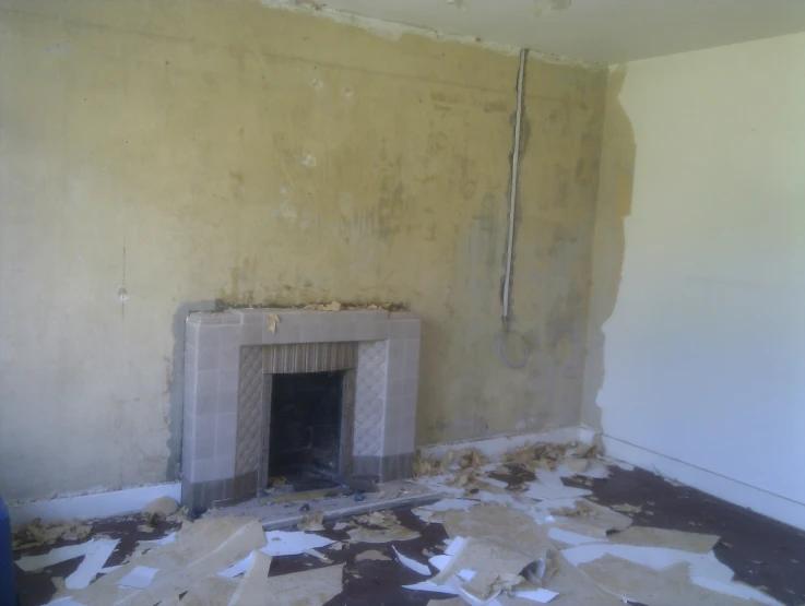 an empty room with a tile fireplace surrounded by rubble