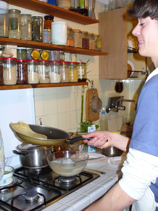 a woman in a kitchen with a stove and shelves above