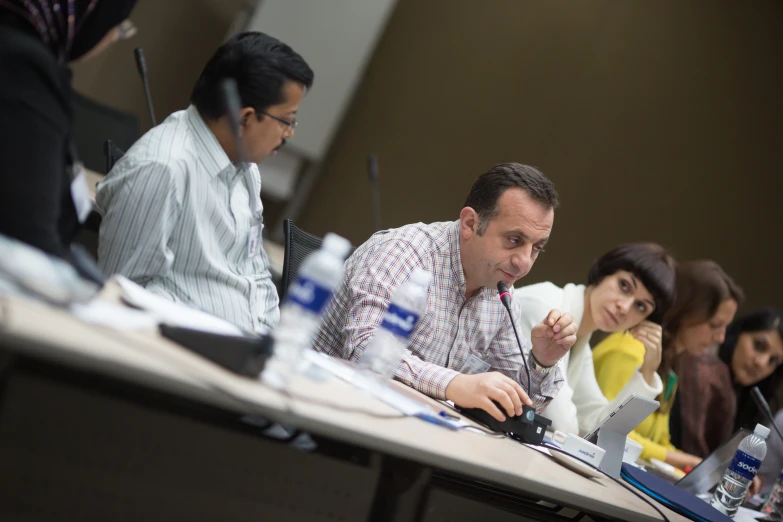 people at a table, looking forward while listening to a presentation