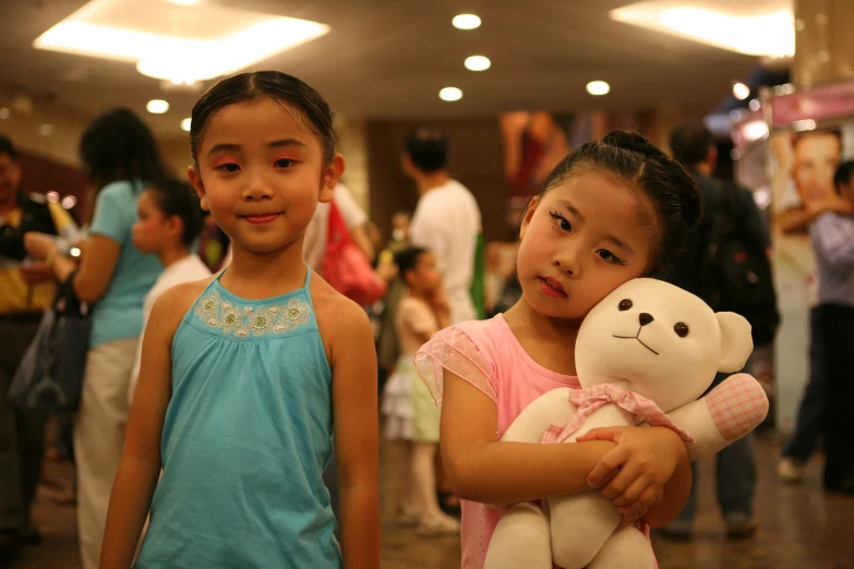 two s who are standing near each other holding a teddy bear