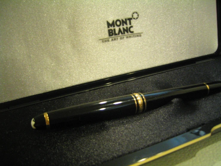 there is a black and gold pen and a silver object on the box
