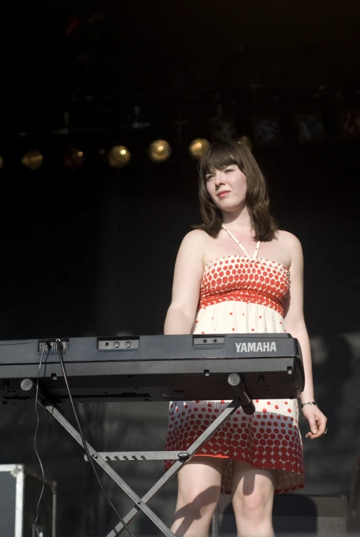 a woman in a dress playing keyboards on stage