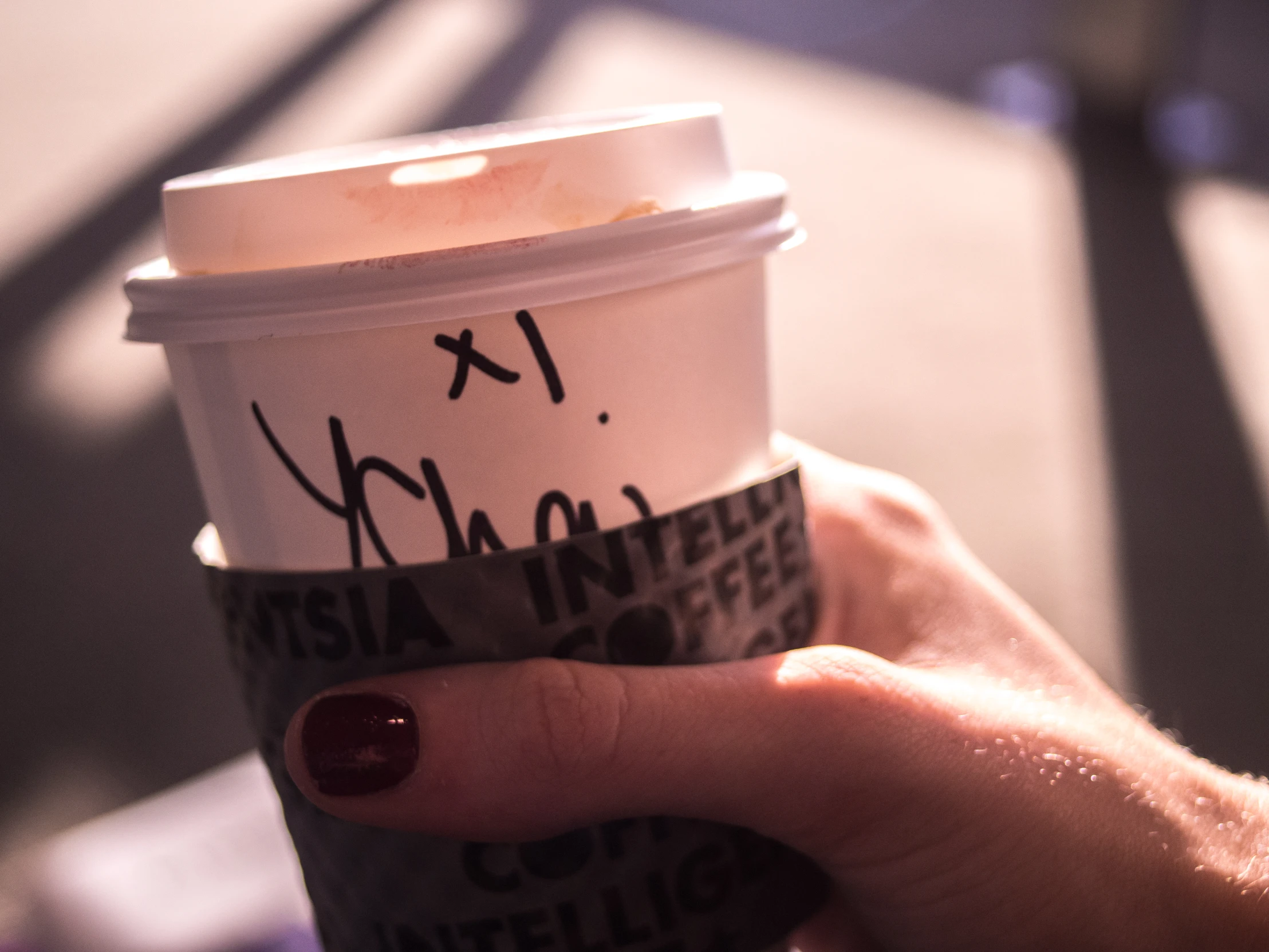 a hand holding a coffee cup with writing on it