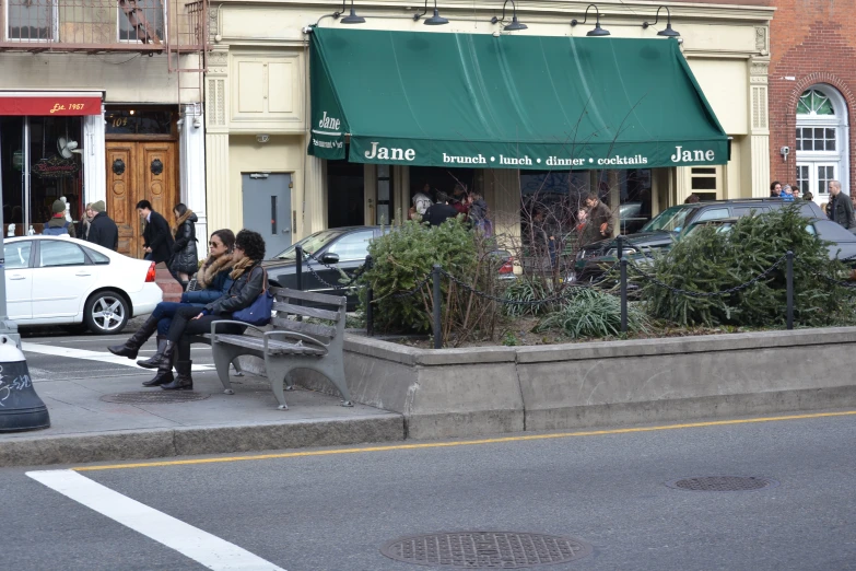 several people sitting at a corner under an umbrella