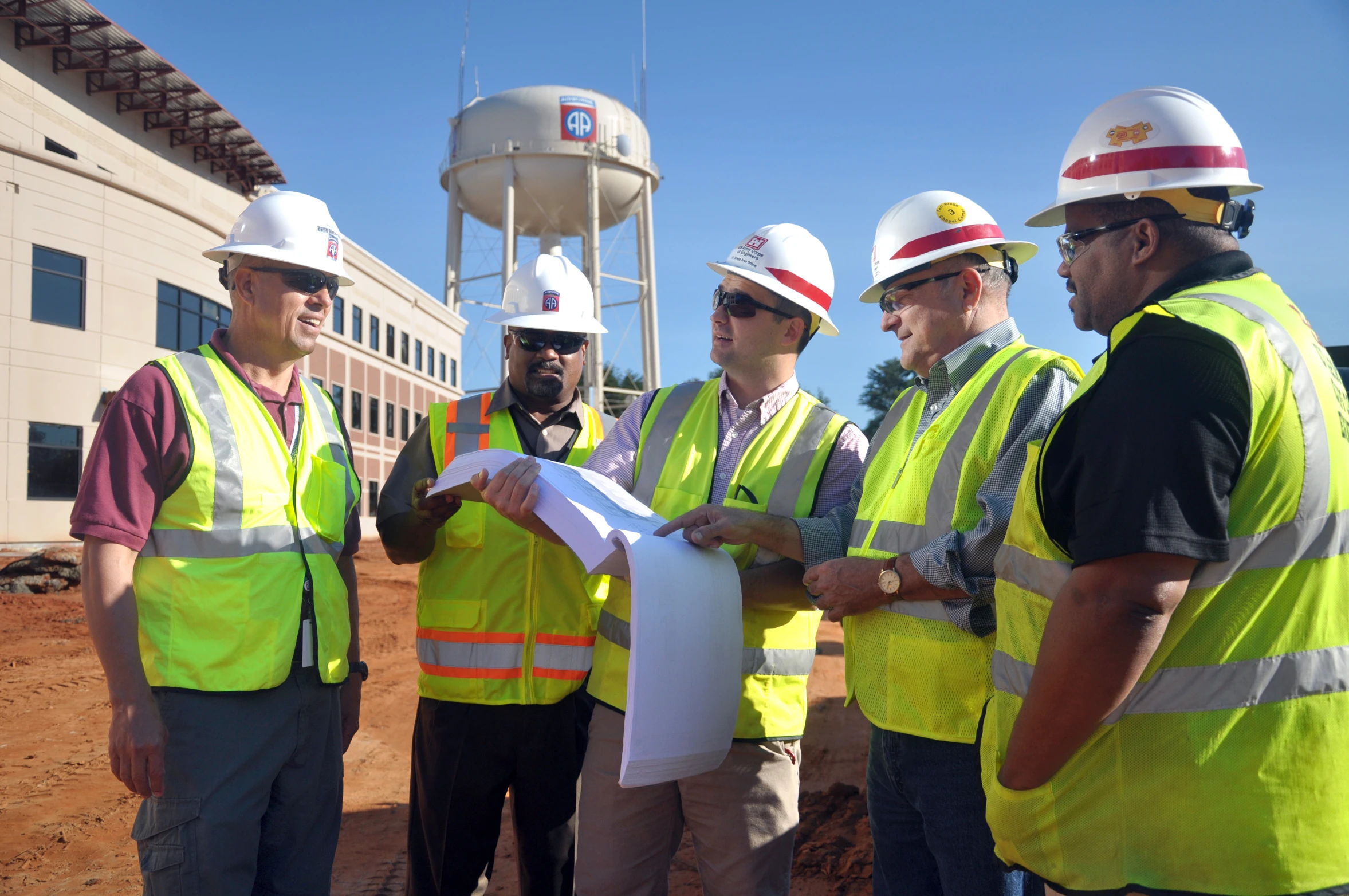 group of men wearing construction safety vests looking at blueprint