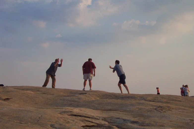 group of people flying kites on sand at beach