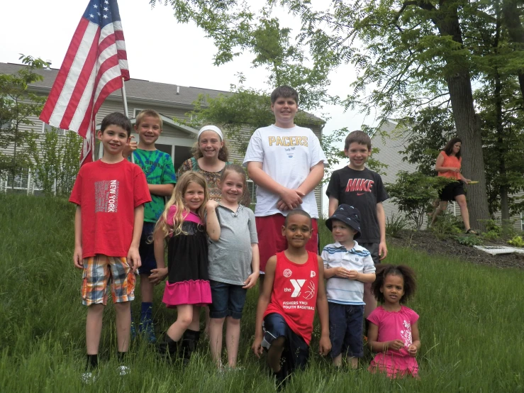 a group of children are standing in a field with an american flag