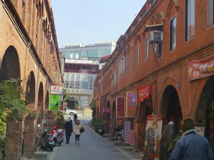 people walking down an alley next to a red brick building