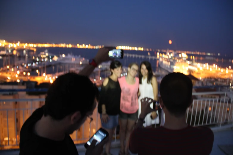 a man taking a po of three beautiful women on a balcony