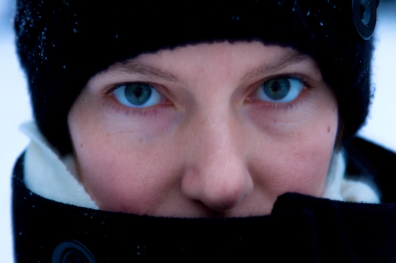 a closeup of the face and blue eyes of a woman with winter gear