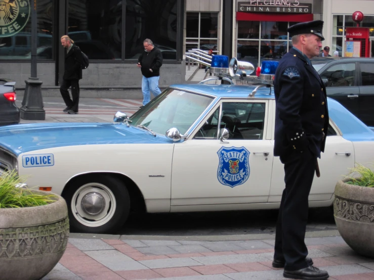 a police officer standing next to an old car