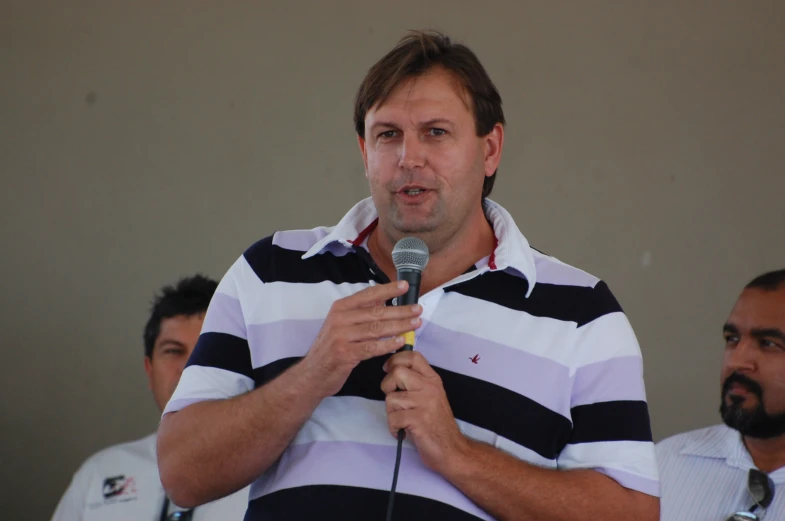 a man standing behind a microphone while talking