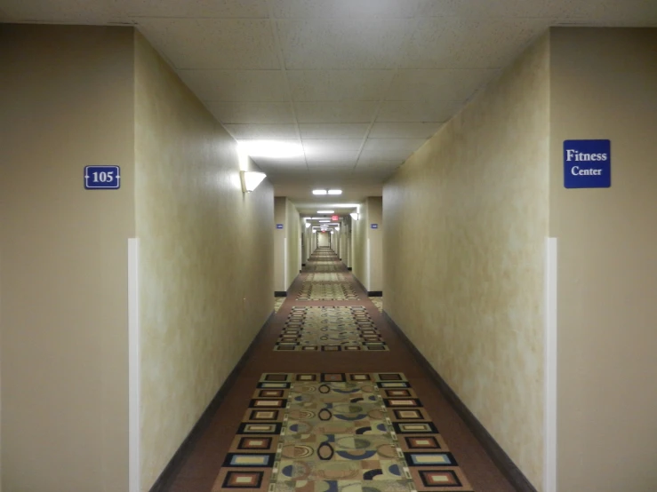 a hallway that has a long carpet and blue sign above it