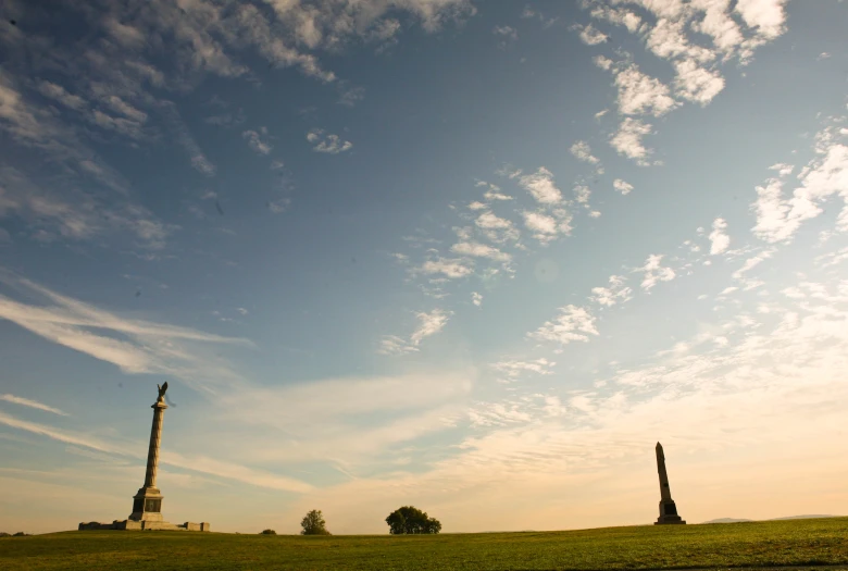 the sky is full of clouds while two park sculptures sit on the grass