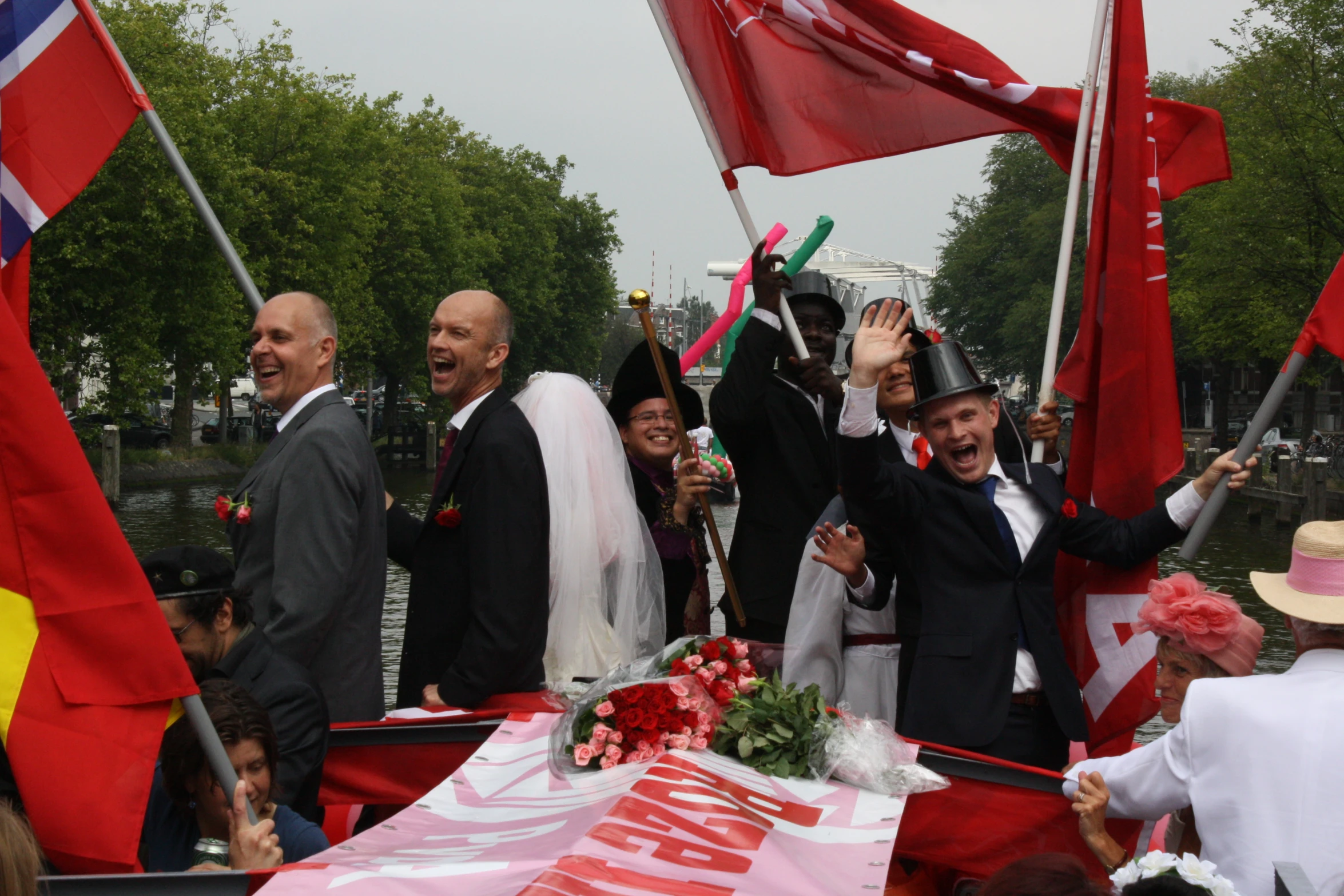 people holding flags waving and walking next to a boat