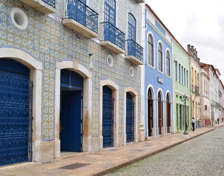 several tall colorful buildings in a street with blue doors