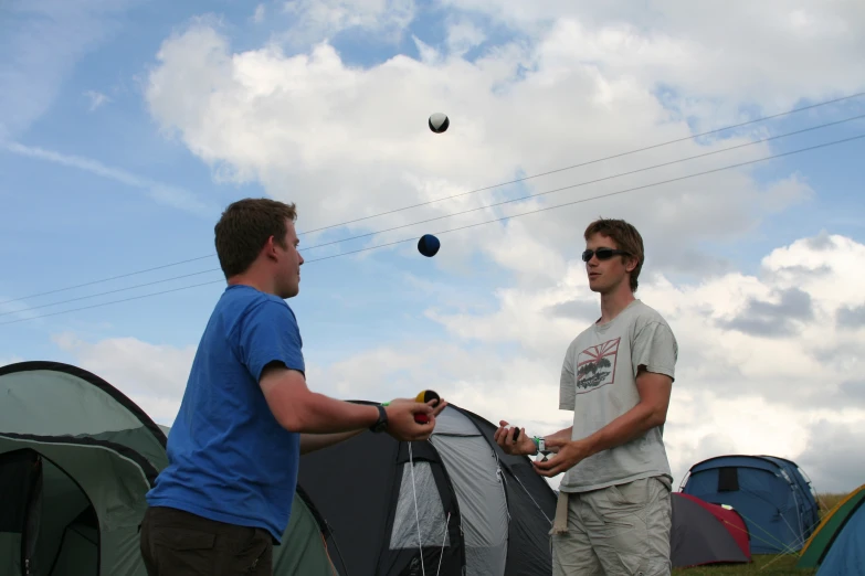 two men with glasses stand in front of tents