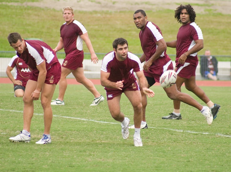 the players in the maroon uniform have crossed their legs and both of them run with a white ball