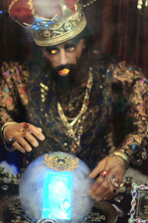 an indian man wearing a headpiece looking at a small device with a glowing light in it