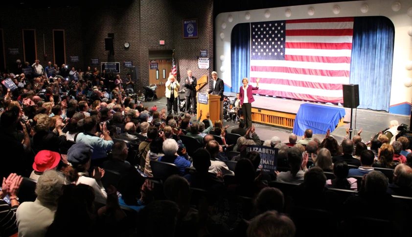 people are sitting on a stage in front of an american flag