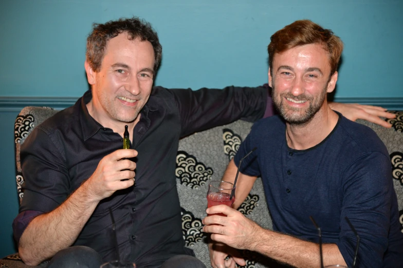 two men sitting on top of a couch together