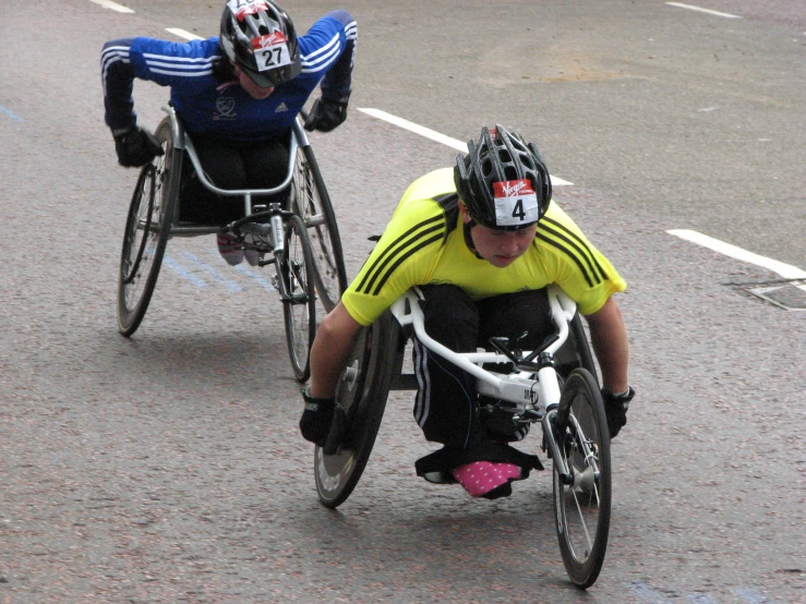 two people in wheelchairs on a street