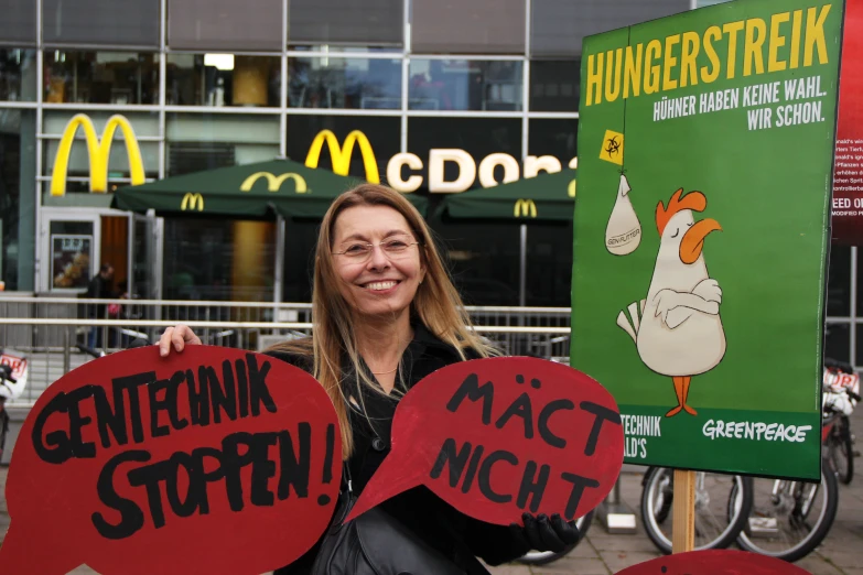 a woman is standing in front of a mcdonald's store holding up signs with the words gettin'n styrofoam on them