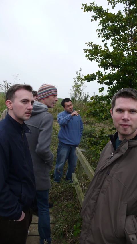 a group of men standing next to each other near the woods