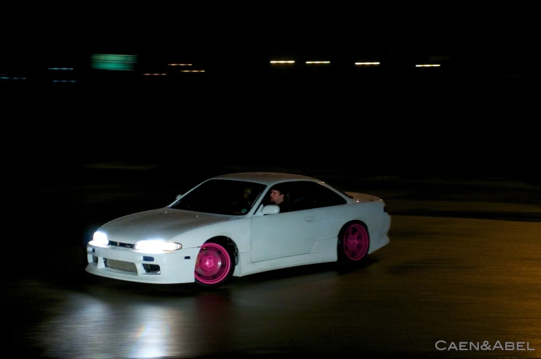 a white car with purple tinted wheels parked in the street