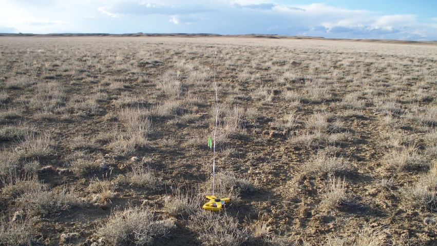 the green pole is attached to a yellow object in a field