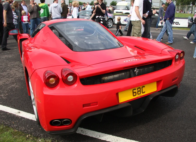 a large number of people are gathered around a large red sports car