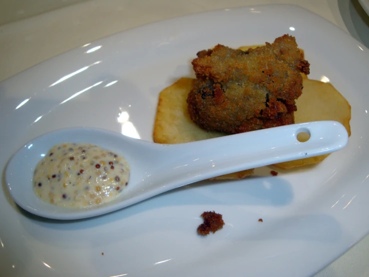 a white spoon is on a small square plate