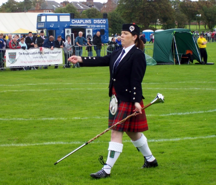 a woman in a kilt walking across the field