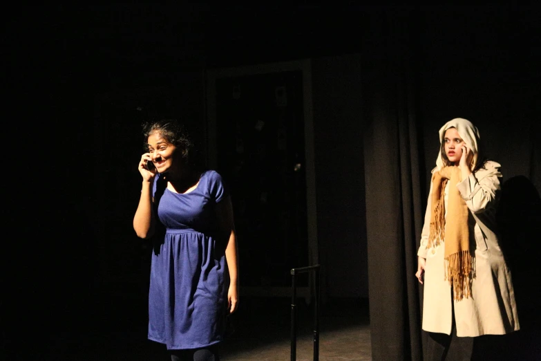 a couple of woman talking on phones in front of an audience