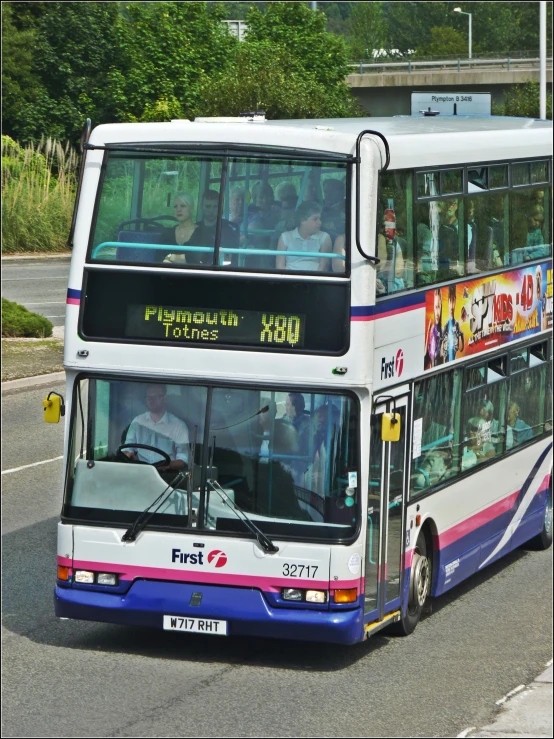 a white double decker bus drives down a busy road