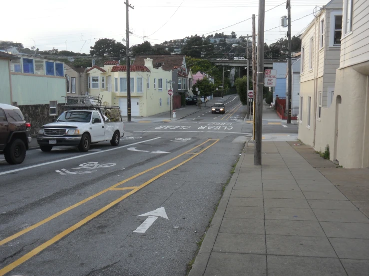 cars are driving down the street by houses