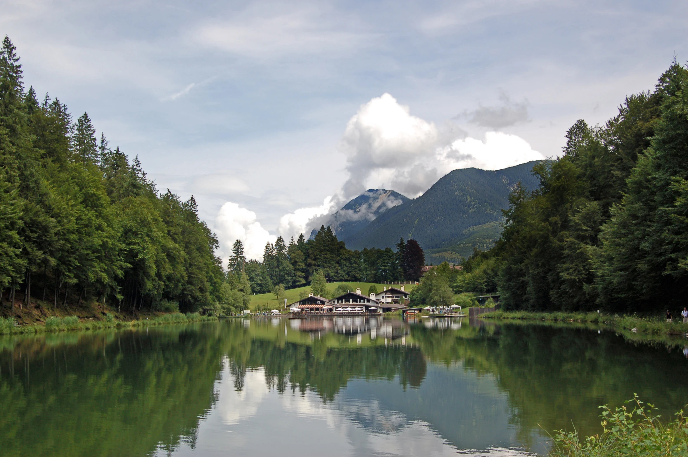 a lake with mountains in the background and people on the dock