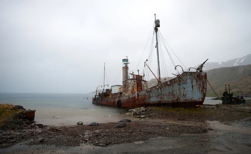 a boat sitting on top of a sandy beach next to the ocean