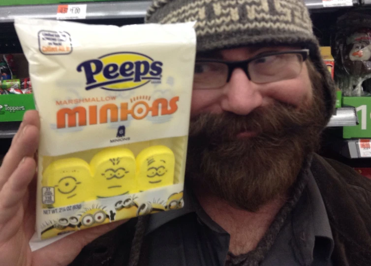 a man wearing glasses and a knitted cap with a pack of peeps minion snacks on it