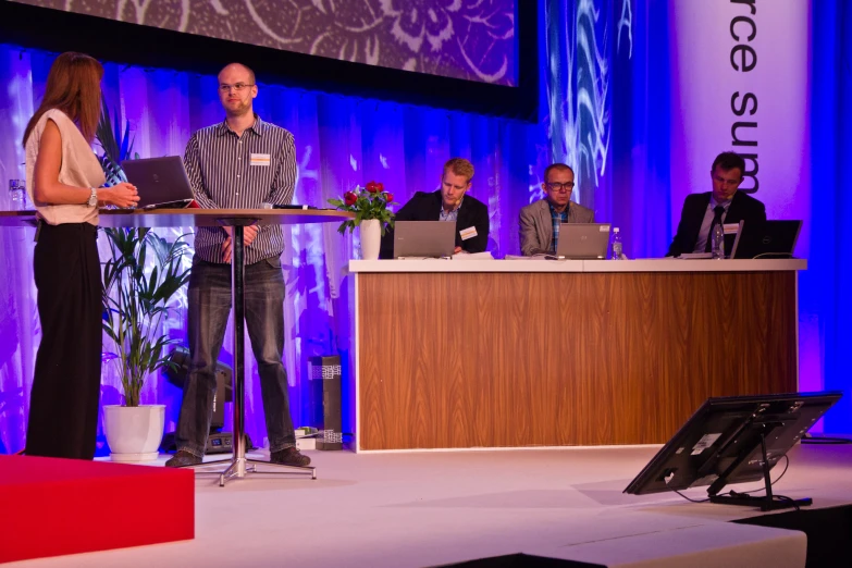 two men and two women standing at podium with laptops on