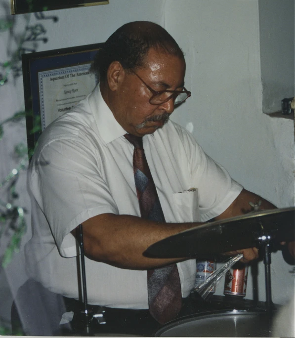 a man with glasses sitting in front of a drumet