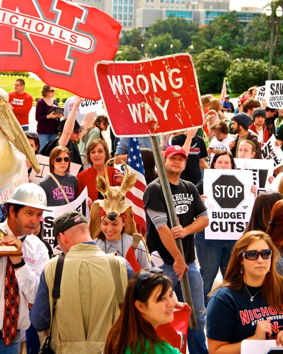 a crowd holding protest signs protesting wrong way