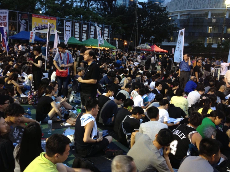 many people sitting on the ground with signs around them