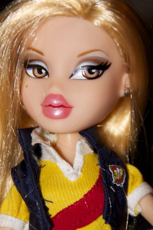 a blond haired doll has a yellow shirt and black and red striped vest